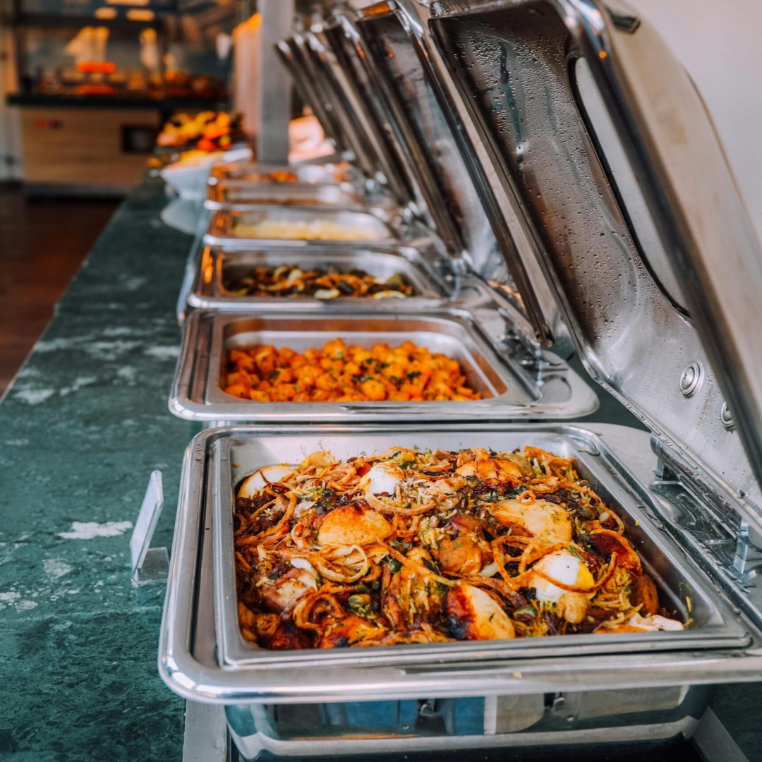 An elegant buffet setup featuring various delicious dishes in stainless steel chafing dishes, perfect for events.