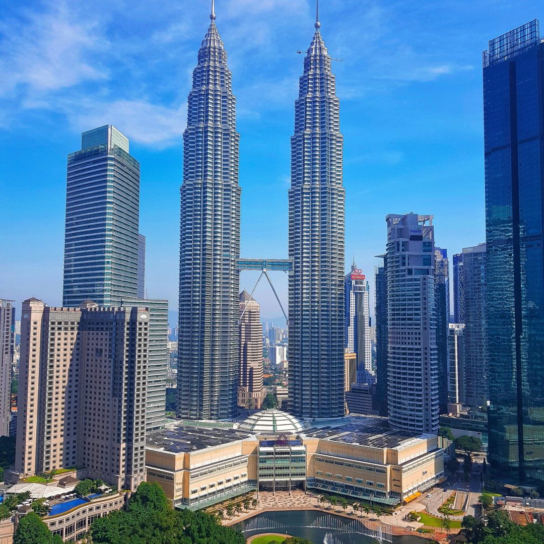 Kuala Lumpur cityscape with iconic Petronas Twin Towers under a clear blue sky.